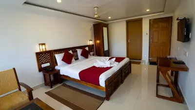a bedroom with a large bed with red and white sheets at Carmel Top Munnar in Munnar