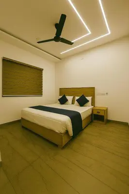 a bedroom with a bed with a ceiling fan at Grandstaykannur in Kannur