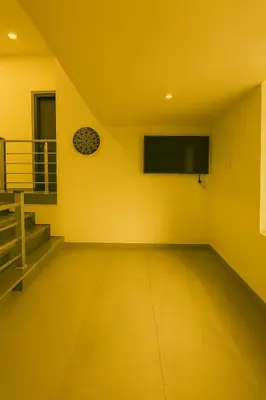 an empty room with a flat screen tv on a yellow wall at Grandstaykannur in Kannur