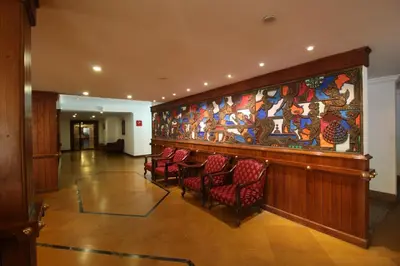 a lobby with chairs and a large painting on the wall at Sopanam Heritage in Guruvāyūr