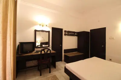 a bedroom with a desk with a computer and a mirror at Sopanam Heritage in Guruvāyūr