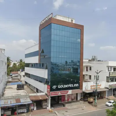 a tall glass building with a sign on it at Goldeye's Inn in Erode