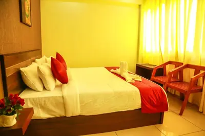 a bedroom with a bed with red and white pillows at AKAN HOTEL AND RESIDENCE in Wayanad