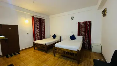two beds in a room with wooden floors at Misty Green Coorg in Madikeri