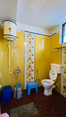 a bathroom with a toilet and a yellow wall at Misty Green Coorg in Madikeri