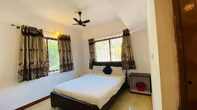 a bedroom with a bed and two windows at Misty Green Coorg in Madikeri