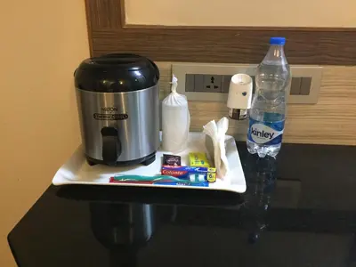 a counter with a coffee maker and a bottle of water at WESTLAND HOTEL- ERODE in Erode