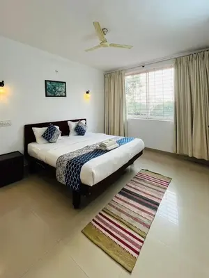 a bedroom with a large bed and a rug at Red Stone Villas in Madikeri