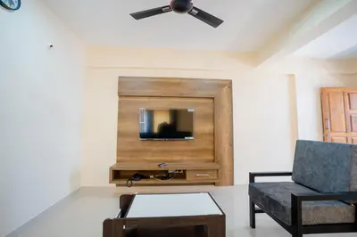 a living room with a tv and a chair at Elegance Serviced Apartment in Mysore