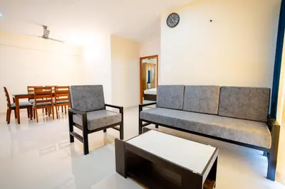 a living room with a couch and a chair and a table at Elegance Serviced Apartment in Mysore