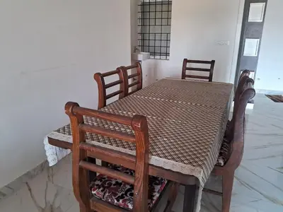a wooden table with chairs and a table and a table and a table and chairs at Royal homes a2 in Kushālnagar