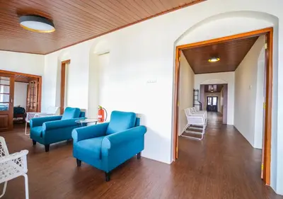 a living room with blue chairs and a table at Lauriston Ooty Town Heritage Bungalow by VOYE HOMES in Ooty