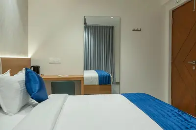 a hotel room with a bed and a desk and a mirror at J Square Inn in Coimbatore