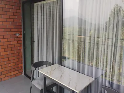a table and chairs on a balcony with a window at WINTEL WILD in Vālpārai