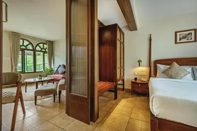 a bedroom with a bed and a living room at Mango Hill Shola Ooty in Ooty