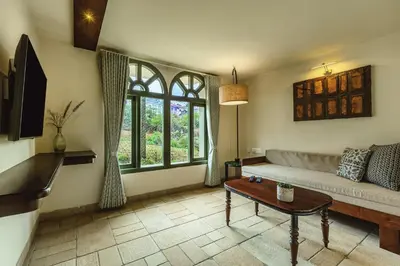 a living room with a couch and a large window at Mango Hill Shola Ooty in Ooty