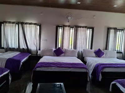 two beds in a room with purple sheets and windows at Royal homes a3 in Kushālnagar