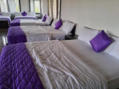 a row of beds with purple pillows in a room at Royal homes a3 in Kushālnagar