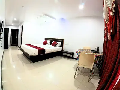 a bedroom with a bed and a table with a chair at The Travellers Nest in Ooty