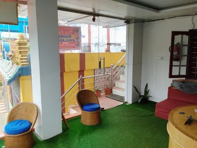 a room with green carpet and chairs and a balcony at The Travellers Nest in Ooty