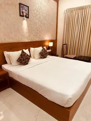 a bedroom with a large bed with white sheets and pillows at Fortune Hills in Palakkad