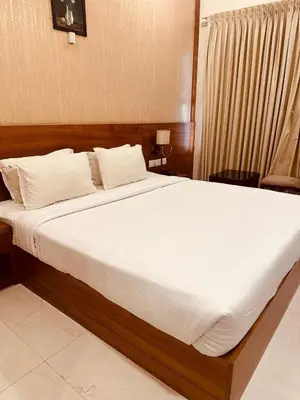 a bedroom with a large bed with white sheets at Fortune Hills in Palakkad