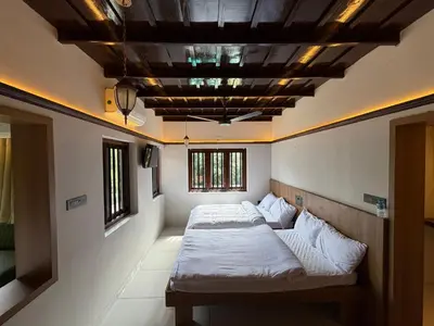 two beds in a room with a coffered ceiling at Mangrove Heritage Home, Chendamangalam in Cochin