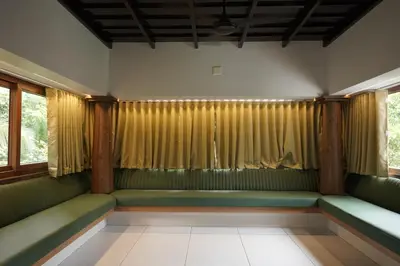 a waiting room with green seats and windows at Mangrove Heritage Home, Chendamangalam in Cochin