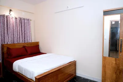a bedroom with a bed with white sheets and a window at HILL PALACE RESIDENCY COORG in Virajpet