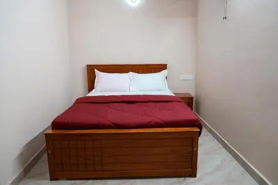 a bedroom with a wooden bed with a red comforter at HILL PALACE RESIDENCY COORG in Virajpet