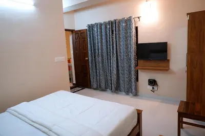 a bedroom with a bed and a flat screen tv at HILL PALACE RESIDENCY COORG in Virajpet