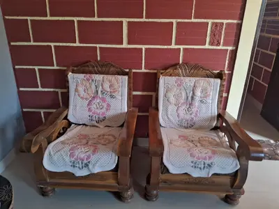 two chairs with floral cushions sitting next to a brick wall at Royal homes a5 in Kushālnagar