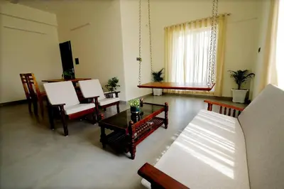 a living room with a couch and a table and chairs at Eazy Homes in Palakkad