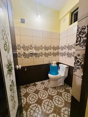a bathroom with a toilet with a blue seat at Rivera Holiday Home in Vythiri