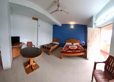 a bedroom with a bed and a table and a couch at Vinayaka Deluxe Lodge in Kushālnagar