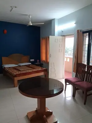 a room with a bed and a table and chairs at Vinayaka Deluxe Lodge in Kushālnagar