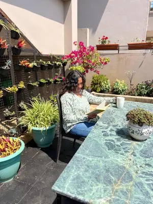 a woman sitting at a table reading a book at Sunset Villa in Coonoor