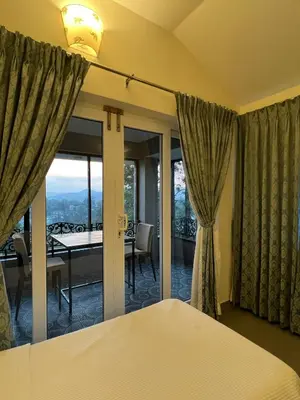 a bedroom with a bed and a dining room with a table at Sunset Villa in Coonoor