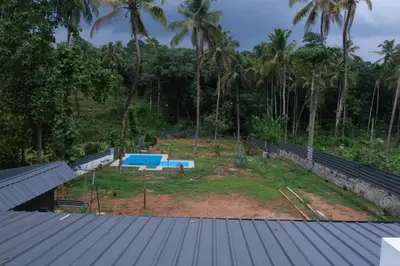 a view of a swimming pool with palm trees at Avian Oasis Homestay in Thattakād