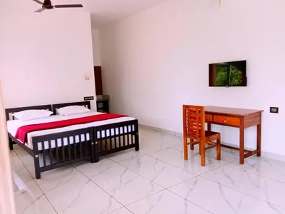 a bedroom with a bed and a table and a desk at Appu's Nido in Pallipuram