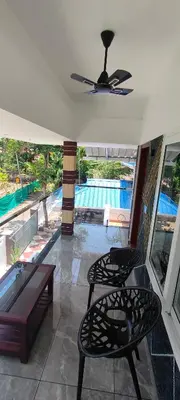 a room with two chairs and a table and a pool at Coastal Den Homestay in Pallipuram