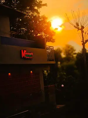 a building with a sign on it with the sunset in the background at Mannath Private Pool Villas at Vellarimala in Wayanad