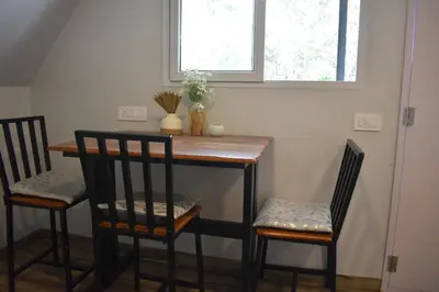 a table with two chairs and a table and two windows at IInfinity Kodaikanal in Kūkkāl