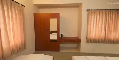 a room with two beds and a vanity and a mirror at ThulasiRams Service Apartments in Coimbatore