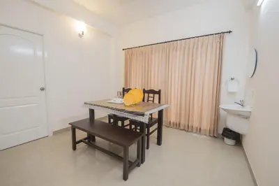 a room with a table and two chairs and a sink at ThulasiRams Service Apartments in Coimbatore