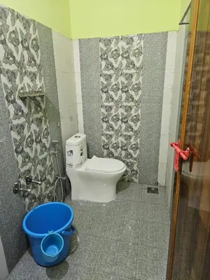a bathroom with a toilet and a blue bucket at Pavithra cottage munnar in Munnar