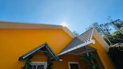 an orange house with a pitched roof at Coastal Grand Resorts - Akshaya in Kotagiri