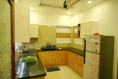 a kitchen with wooden cabinets and a black refrigerator at Home stay - Near Cochin Airport in Angamali
