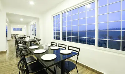 a restaurant with tables and chairs and large windows at Treebo Skydale Inn & Suites With Mountain View in Ooty