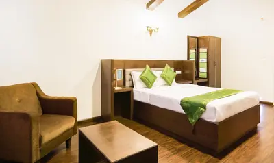 a hotel room with a bed and a chair at Treebo Skydale Inn & Suites With Mountain View in Ooty